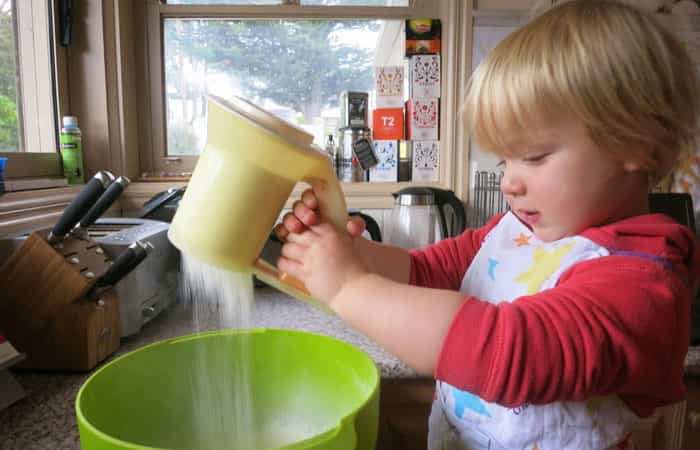 Cocinar con niños: Niño tamizando harina sobre un cuenco