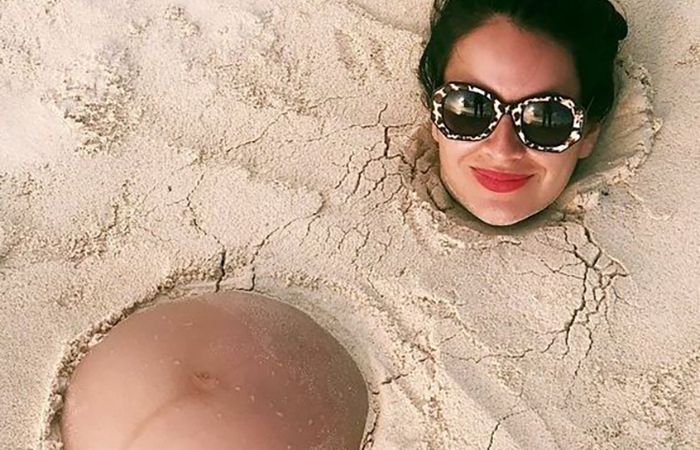 Embarazada cubierta de arena en la playa