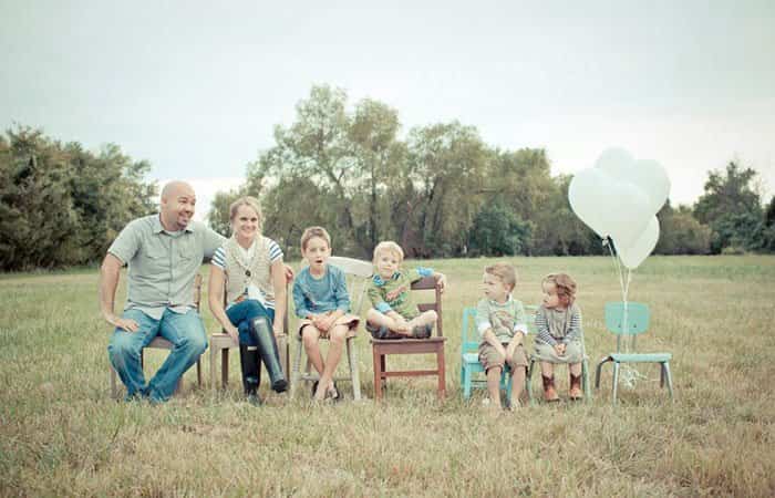 La familia sentada en varias sillas, la última vacía y con globos