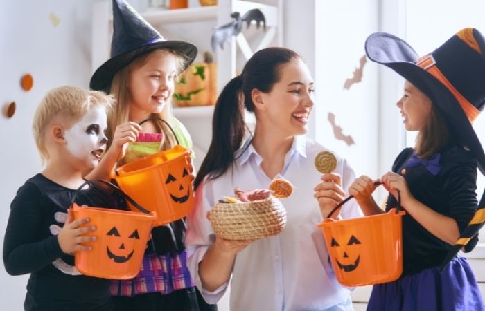 Mujer dando dulces a unos niños en Halloween