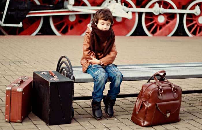 Niño rodeado de maletas en una estación de trenes