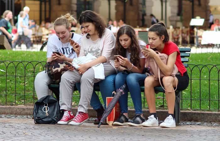 Grupo de adolescentes prestando atención a sus móviles en vez de una conversación. Esto se conoce como phubbing