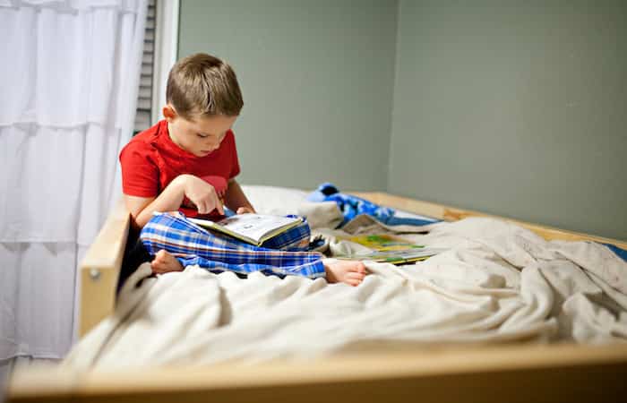 Rutina para dormir mejor: niño leyendo en la cama