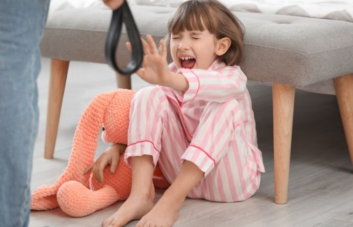 Niña gritando y mano masculina con cinturón