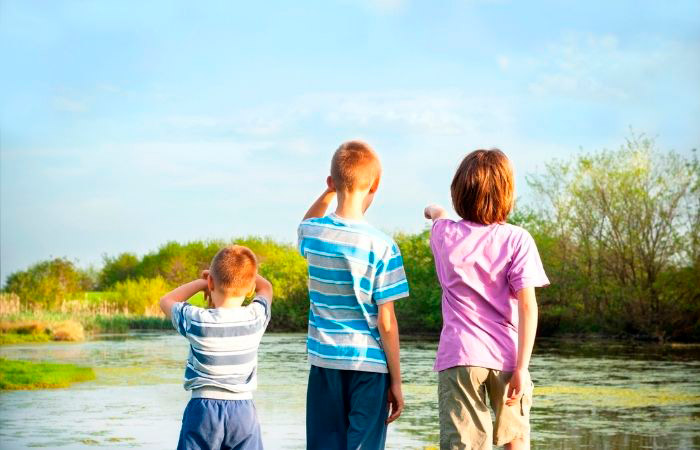 niños observando la naturaleza en un lago. Rutinas de vacaciones