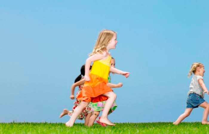 niños corriendo descalzos por la hierba
