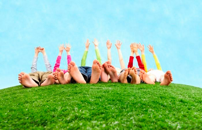 Niños descalzos tumbados en la hierba. Juegos para hacer con los pies