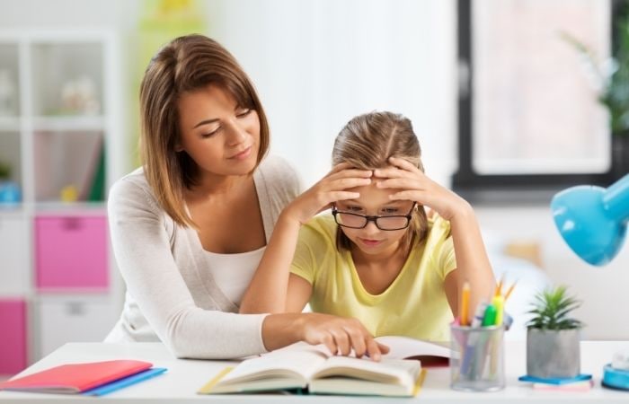 Hacerle los deberes a tu hijo: madre ayudando a su hija