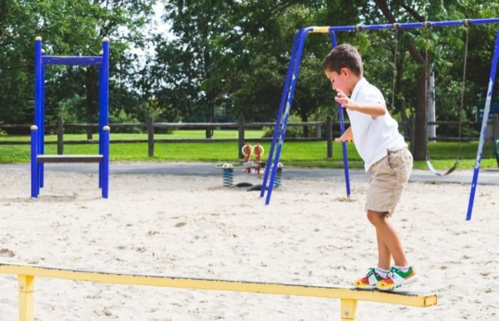 jugar en el parque: niño en la zona recreativa caminando por una barra