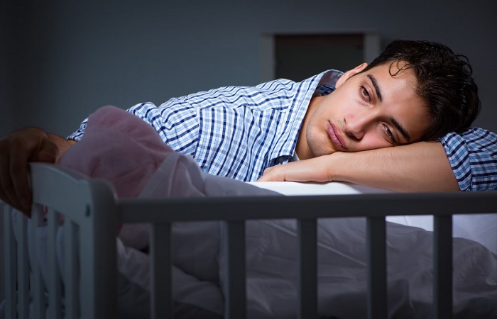 El Trastorno Obsesivo Compulsivo postparto: padre cansado ante la cuna de su bebé