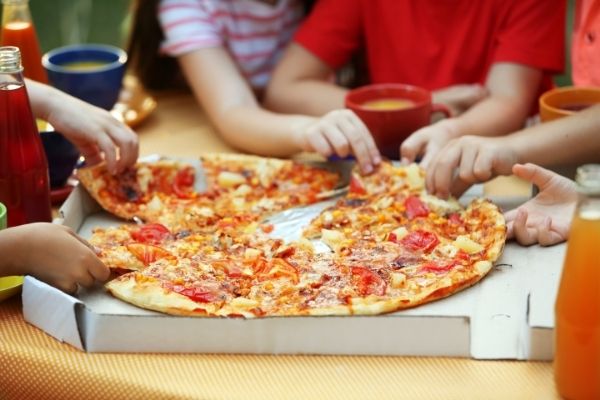 niños comiendo pizza: alimentos procesados