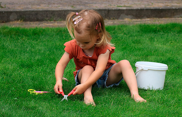Un jardín para los niños: una niña corta el césped con tijeritas