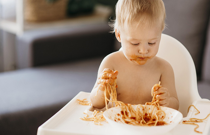 bebé comiendo espaguetis con tomate con sus manos